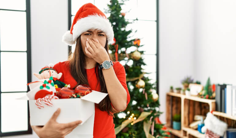 Woman holding her nose because of smelly Christmas tree